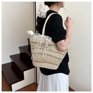 Detail of hand-woven straw tote bag with elegant white lace bow and floral accent