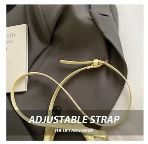 Detail of adjustable pale yellow handbag strap with woven ends and metallic buckle