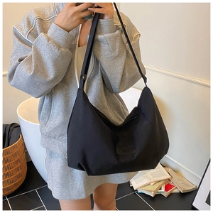 Minimalist black large capacity crossbody hobo bag styled on model in bright indoor setting