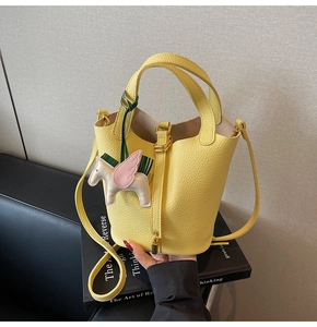 Detail of lemon yellow bucket bag with lychee texture leather and pegasus charm