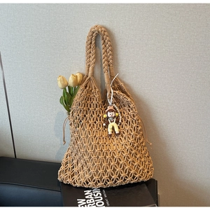 Detail of woven tote bag with hollow grid design, inner lining and retro doll pendant