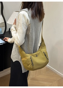 Détail du sac demi-lune jaune moutarde avec logo M rond et tirettes de zip tissées