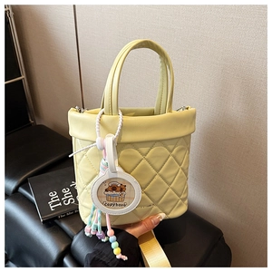 Detail of light yellow quilted handbag featuring a cute capybara pendant and beads