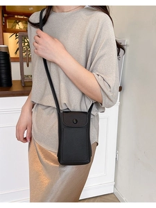 Elegant black lychee texture crossbody phone bag with flap closure on model in cafe