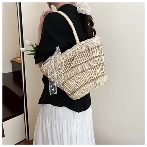 Detail of hand-woven straw tote bag with brown wavy patterns and white lace ribbon deco