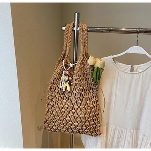Detail of brown hand-woven hollow tote bag with a cute charm and drawstring closure