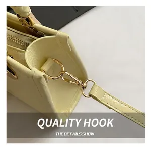 Detailed macro view of golden metal hook and embossed leather texture on a beige handbag