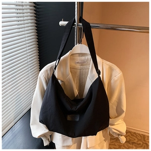Close-up of black nylon hobo bag featuring wide strap and minimalist leather brand patch