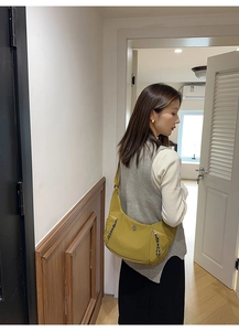 Détail du sac hobo en nylon jaune gingembre avec poche zippée et logo métallique
