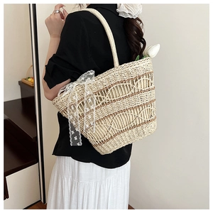 Close-up of a woven tote bag with a white lace bow detail and stylish shoulder strap