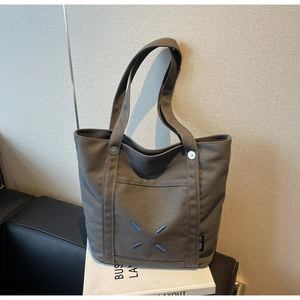 Detail of taupe canvas tote bag with signature four-corner stitching and rivet reinforcement