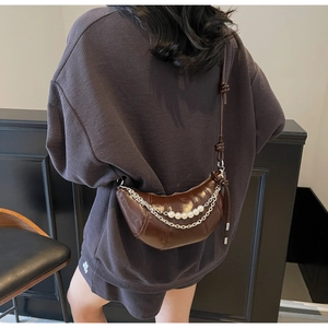 Detail of dark brown croissant bag with pearl chain and glossy leather texture