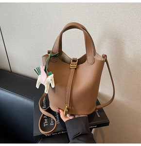 Close-up of brown pebbled leather bucket bag with gold padlock and horse charm