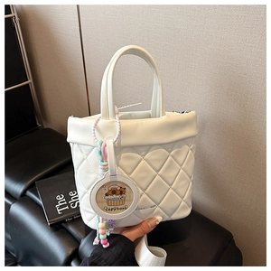 Detail of white quilted crossbody bag with cute capybara pendant and pearl beads