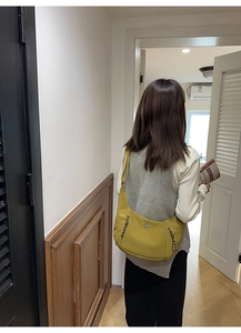 Vue détaillée d'un sac bandoulière jaune en nylon avec tirettes tressées en usage quotidien