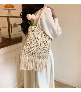 Detailed shot of cream woven tote bag with diamond pattern and decorative long tassels