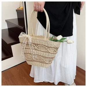 Detail of hand-woven straw tote bag featuring elegant lace bow and round dual handles