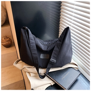 Detail of waterproof nylon crescent bag with leather logo tag and wide shoulder strap