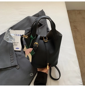 Close-up of black lychee grain leather bucket bag with gold lock and horse charm