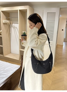Détail du sac croissant en nylon noir avec poches zippées et emblème logo rond