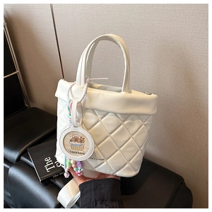 Detailed shot of white quilted leather bucket bag with cute capybara charm and bead details