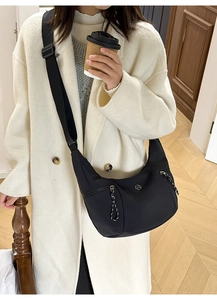 Détail du sac bandoulière croissant en nylon noir avec large sangle et poches zippées