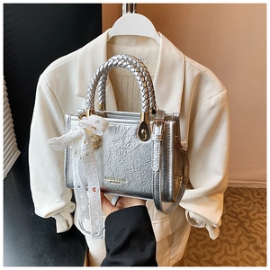 Detail of silver pleated handbag with woven handle, lace bow, and pearl accents