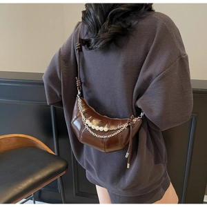 Detailed back view of model wearing dark coffee crescent bag with silver pearl chains