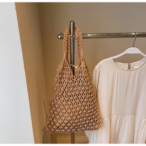 Detailed view of camel-colored woven tote bag with cutout hollow design on a hanger