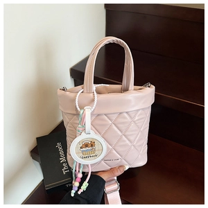 Detailed view of pink quilted bucket bag with a cute Capybara charm and wide strap