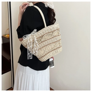 Detail of woven straw tote bag with elegant white lace bow decoration for summer