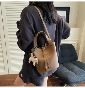 Detailed back view of a brown leather bucket bag with gold lock and pony charm