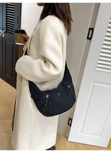 Détail du sac bandoulière noir en croissant avec logo M en métal et tirettes à cordon