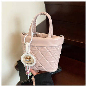 Detail of pink quilted bucket bag featuring a capybara charm and a round top handle