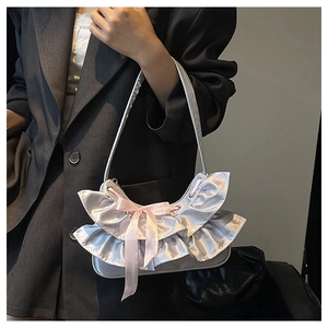 Detail of silver pleated handbag with pink bow showing ruffled satin fabric texture