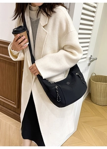 Détail du sac bandoulière croissant en nylon noir avec poches zippées et logo M métallique