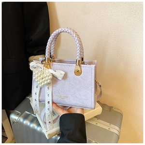 Detail of light purple handbag with woven handle and elegant pearl lace charm