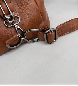 Close-up of gunmetal hardware and adjustable wide strap on brown pebbled leather bag