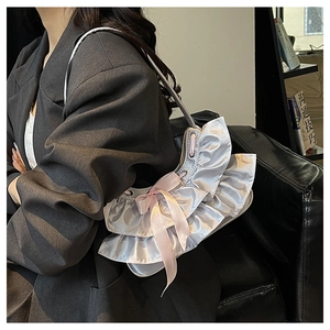 Detail of silver ruffled satin handbag featuring a delicate pink silk bow decoration