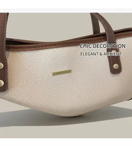 Dettaglio della borsa tote crema testurizzata con manici marroni e finiture in metallo oro