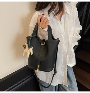 Detail of black pebbled leather bucket bag with gold hardware and horse charm