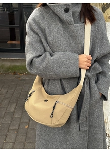 Détail du sac hobo beige montrant les poches zippées et la large bandoulière réglable