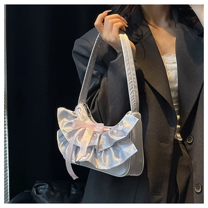 Detailed view of silver satin handbag with layered ruffles and pink bow on grey suit