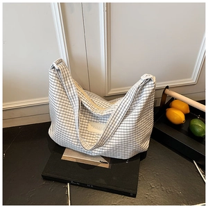 Close-up of black and white houndstooth canvas shoulder bag with leather logo patch