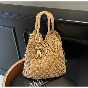 Detail of khaki macrame woven tote bag featuring an adorable cartoon doll charm