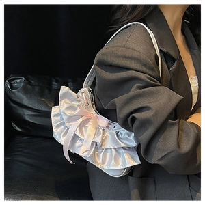 Detail of silver satin ruffled shoulder bag with elegant pink ribbon bow decoration