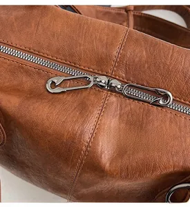 Macro detail of brown leather bag with unique safety pin metal zipper puller design