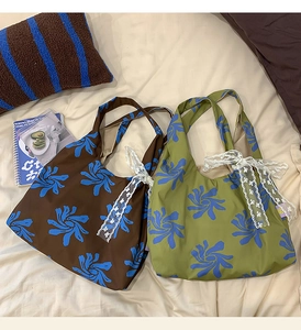 Detailed close-up of nylon dumpling bag with blue floral print and white lace bow