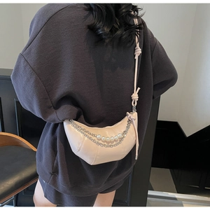 Detail of light pink half-moon bag with quilted texture, pearls, and knotted strap