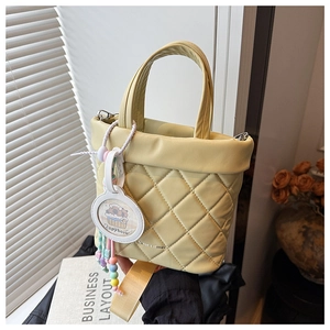 Detail of cream quilted bucket bag with wide strap and cute capybara charm accessory